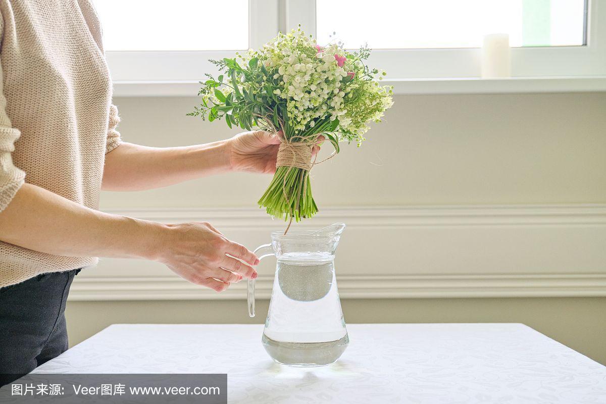 一个女人手里拿着一束鲜花放在桌上的花瓶里