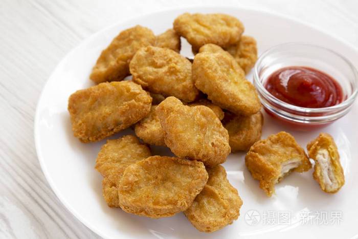 chicken nuggets with ketchup on a white plate on a white wooden