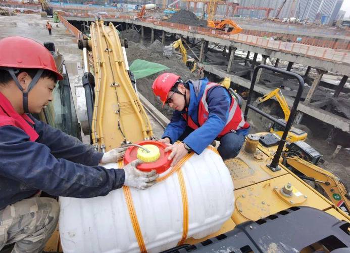 在建邺区一建筑工地上,工人们正在挖掘机上安装喷淋设备.