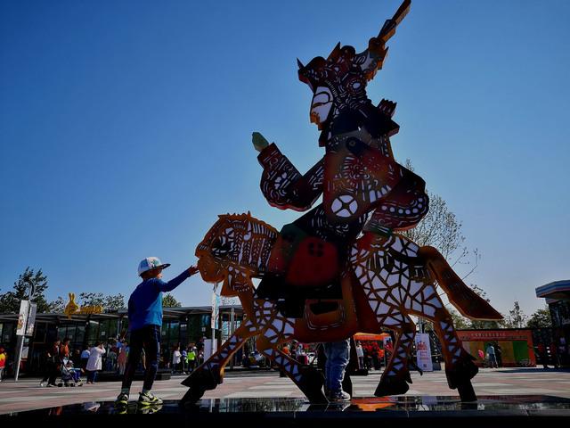 5月1日,河北唐山皮影主题乐园,一位小朋友站在皮影雕塑旁玩耍.