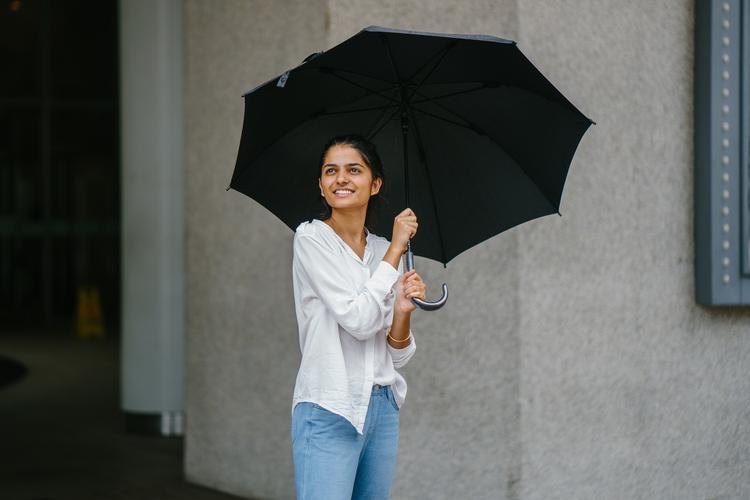一个穿白色衬衫的女人拿着一把黑色雨伞