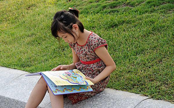 在草地上看书的小女孩