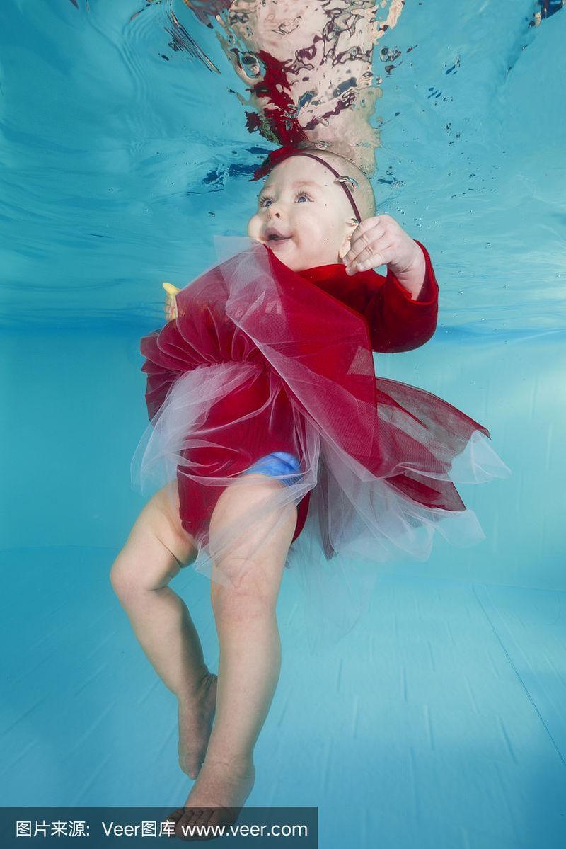 穿着红裙子的有趣的小女孩在游泳池的水下游泳
