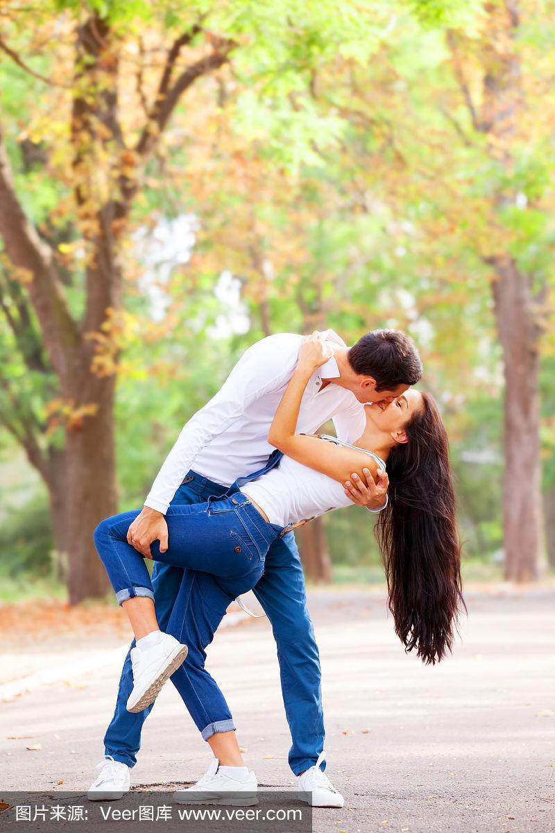 一对青少年情侣在秋天的公园里接吻
