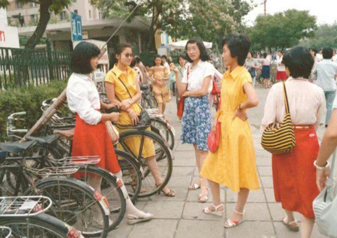 在20世纪90年代的北京街头,几位年轻的女性聚集在一起,她们在自行车