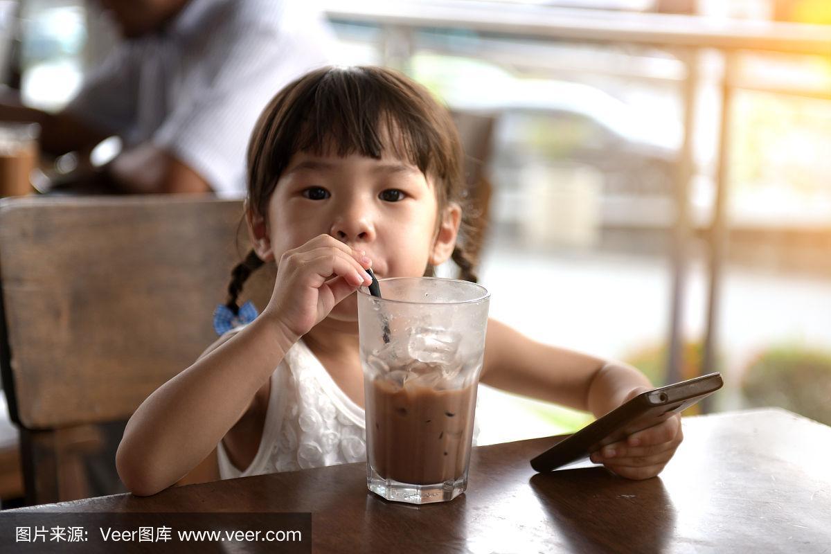 一个亚洲小女孩在咖啡馆喝酒