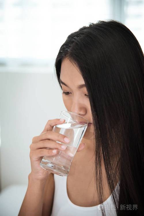 在她的卧室里的亚洲女人喝水