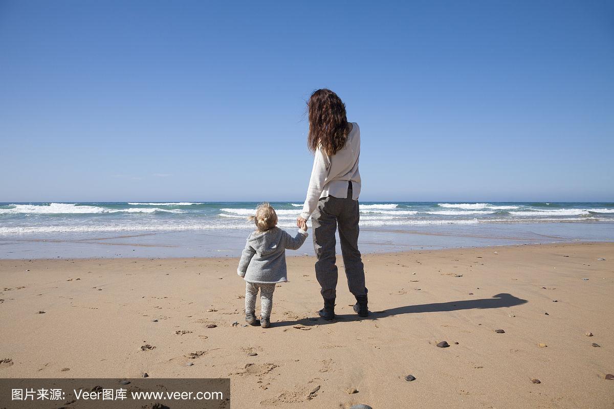 孩子和妈妈在海滩上牵着手
