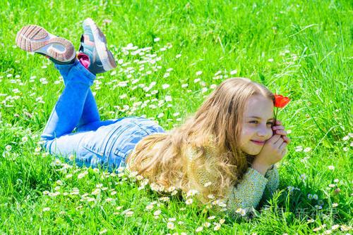 春天的喜悦图片的小女孩躺在草地上拿着红色的郁金香摆姿势拍照.