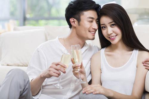 快乐的年轻情侣在客厅喝香槟