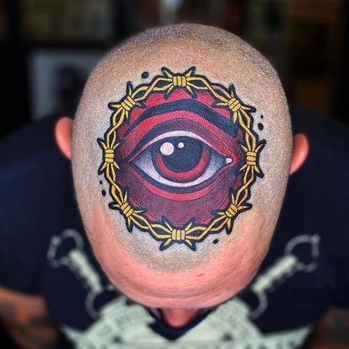 头部正中位置的被荆棘铁丝围绕的红色眼睛纹身图案