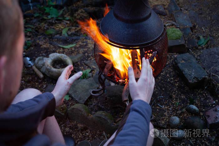 那人在开火前用手取暖.露营概念与户外明火火焰.准备烧烤火