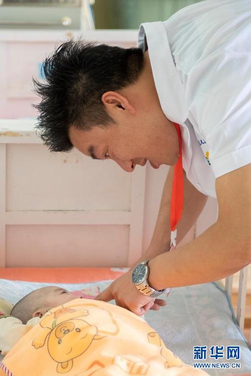 在太原市社会(儿童)福利院,党龙祥在照看一名婴儿(5月26日摄).