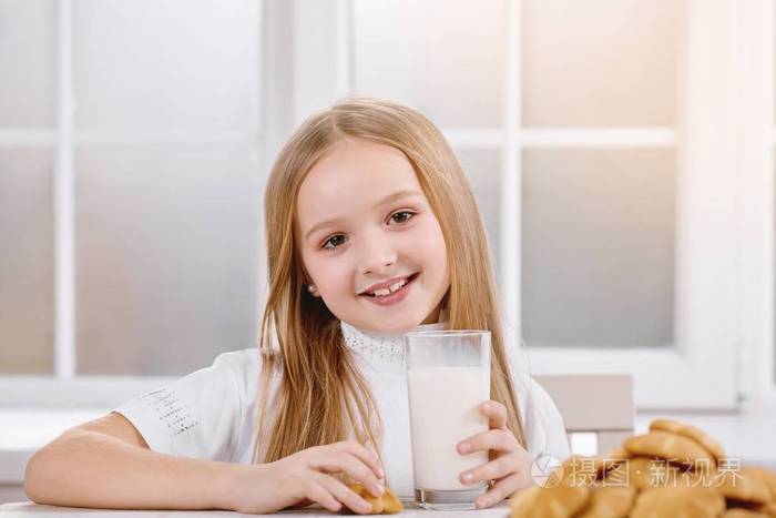 微笑的小女孩喝牛奶与曲奇饼