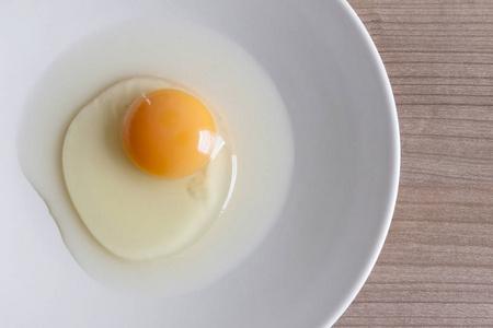 鸡蛋煮早餐, 蛋白形式蛋黄和蛋白在白色的背景,或纯木制的桌子上照片