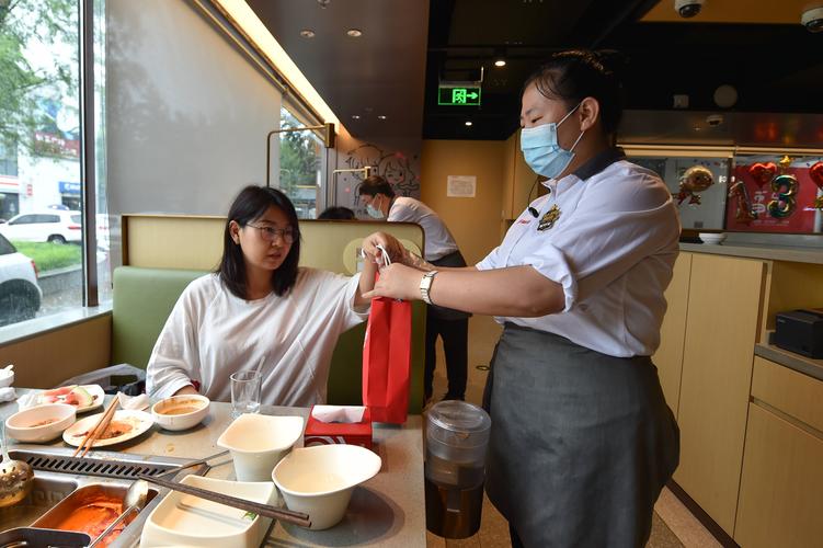 在天津一家火锅餐厅内,服务员在顾客用餐后将需要打包的食物交给顾客
