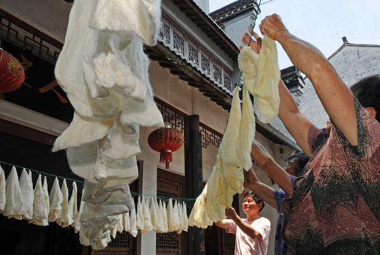 6月12日,王一士(左)和村民在浙江湖州南浔区辑里湖丝博物馆晾晒用于