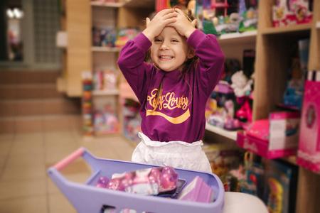 可爱的小女孩在买玩具.玩具店里可爱的女人.快乐小女孩选玩具照片