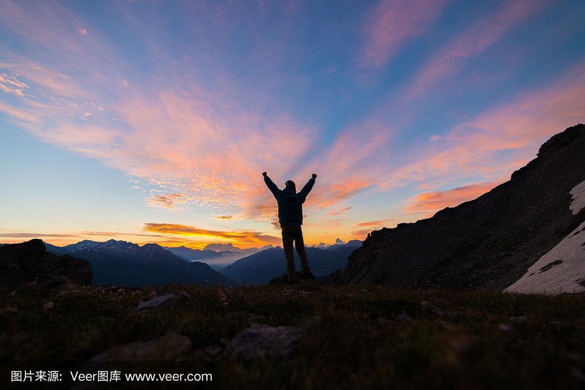 男人站在山顶伸开双臂,日出淡色天空美景,征服成功领袖理念.