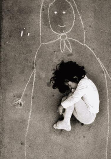 图为:伊拉克孤儿院,一个小女孩在水泥地上画了一个心中的妈妈,然后她