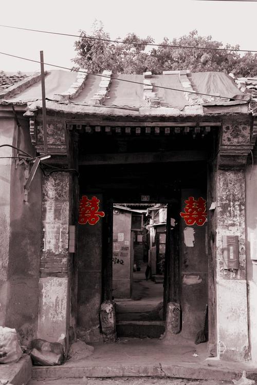 但看北京老城区胡同里的一间破旧的老房子和双喜字显得特别有冲突