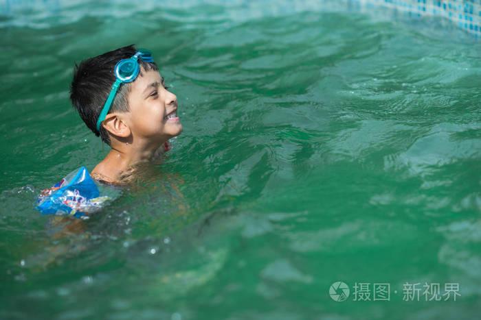 那个小男孩, 额头上戴着护目镜的黑发女郎快乐地沐浴在水中.照片-正版
