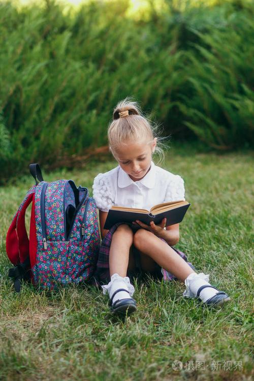 小女孩坐在草地上看书.小学生小学
