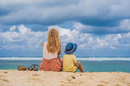 母亲和儿子在沙滩上休息, 欣赏迷人的梅拉斯蒂海滩与绿松石水, 巴厘岛