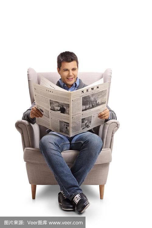 一个年轻人坐在扶手椅上看报纸