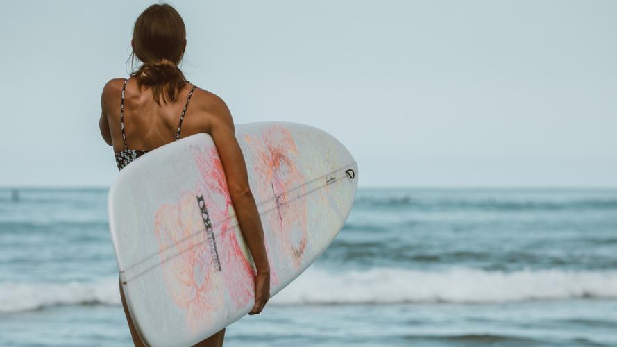 海边抱着冲浪板的女子图片-人物壁纸-高清人物图片-第