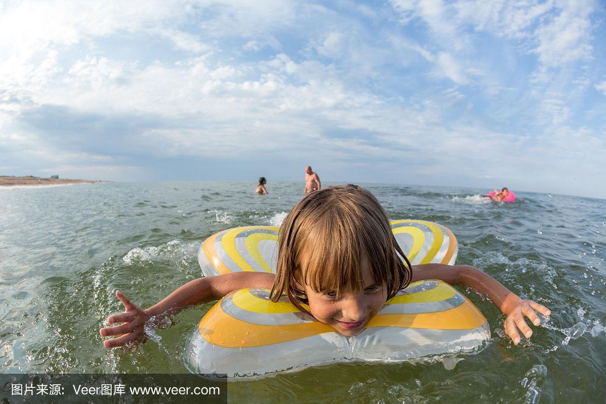 肖像,快乐的小女孩游泳在一个充气圈的海上,广角景观