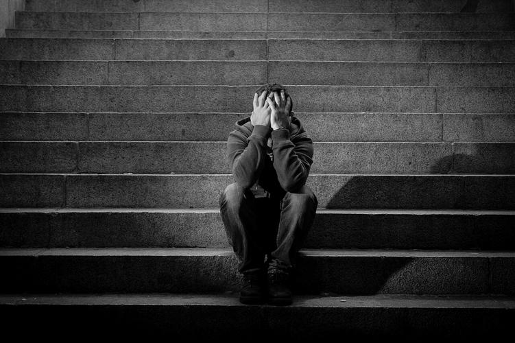 绝望的年轻男子捂着脸坐在阴暗楼梯上孤独的男人失败难过烦躁恼火烦躁