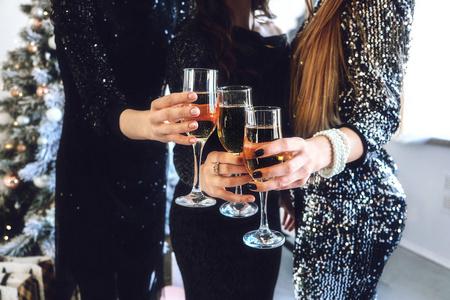 干杯2020女性手特写镜头香槟.在家里,俱乐部里,一群人用香槟长笛欢呼.