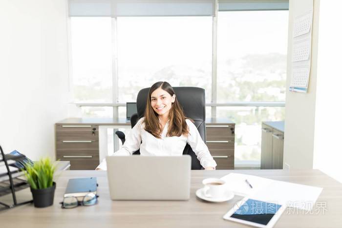 坐在办公室办公桌前微笑的女性财务顾问的画像
