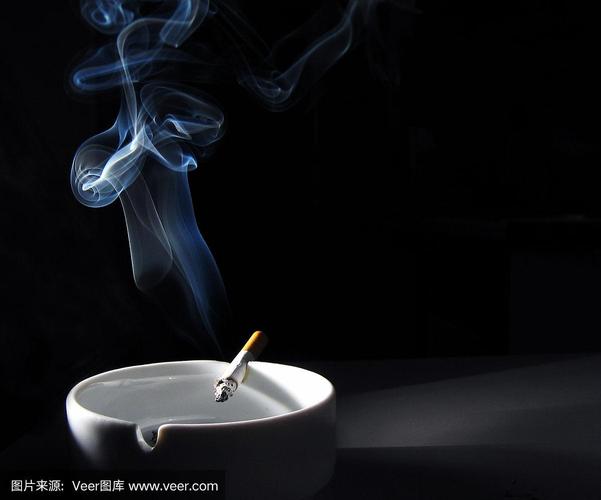 黑色背景的白色烟灰缸里点燃的香烟
