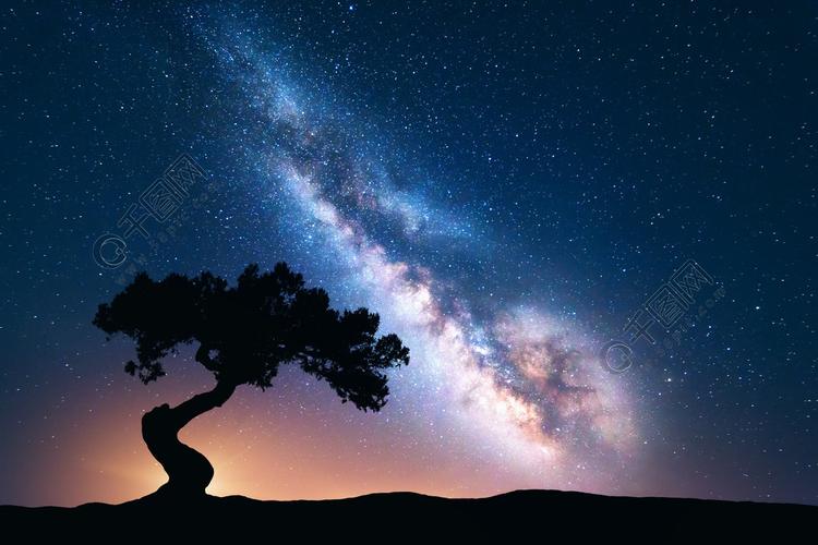 银河系与山上孤独的老歪树五颜六色的夜景与明亮的银河满天星斗的天空