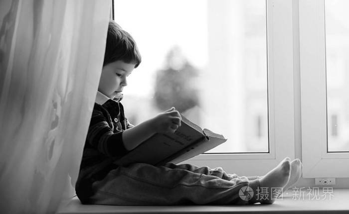 这个小男孩正在看书那孩子坐在窗边