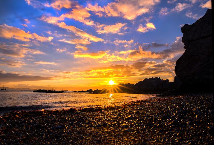 大连湾的太阳冉冉升起,璀璨的阳光照亮了天空和大海,连沙滩也染上了