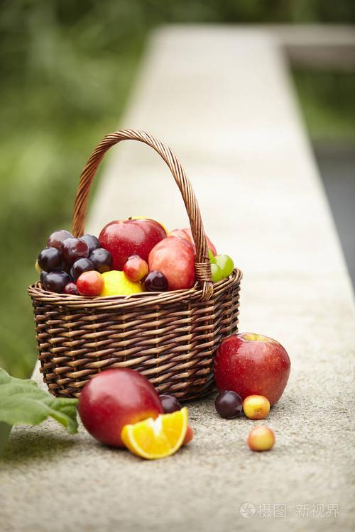 在户外石凳上野餐的篮子里的什锦水果