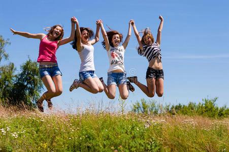 四位快乐的年轻女性朋友在蓝天上跳得很高照片