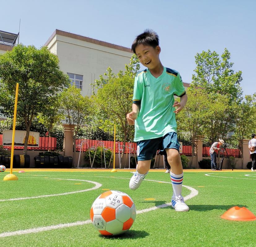 5月16日,青岛市城阳区顺德居幼儿园的小朋友们在教练指导下练习足球.