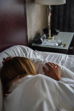 卧床睡觉的女人早上躺在旅馆房间里睡觉的成年妇女