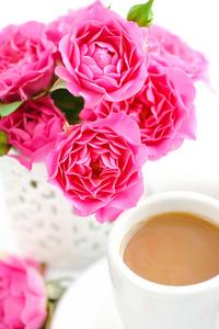 杯的咖啡和粉色的玫瑰花,在白色背景上照片