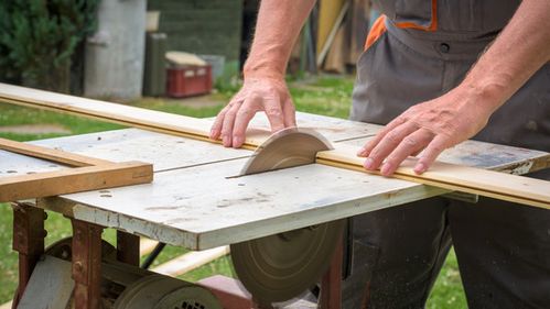 圆耳朵木匠用电动圆锯切割木板的工作照片