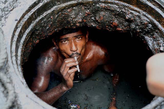 站在化粪池中疏通管道 印度掏粪工人的辛酸生活