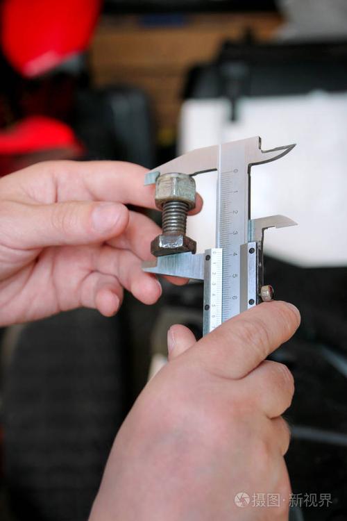 机械师正在用不锈钢卡尺检查和测量汽车修理厂的螺丝尺寸.