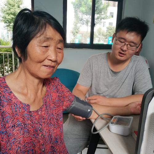 图为王博宇同学在为社区居民测量血压