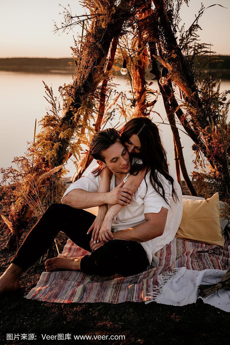 一对年轻夫妇在海边的小屋里拥抱亲吻.浪漫的爱情故事.