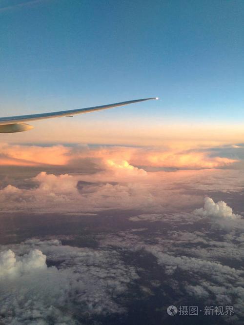 从飞机的窗户到机翼的景色和云层上方美丽的日落.