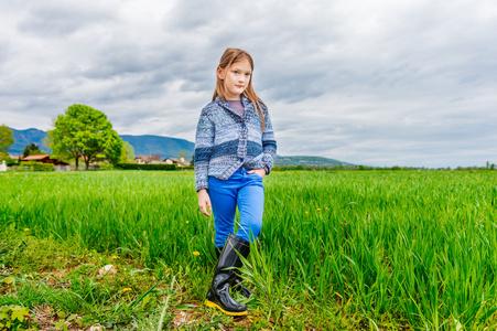 时尚肖像的可爱的小女孩,7 岁,身穿蓝色长裤,针织外套和黑雨靴照片